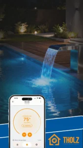 Piscina iluminada à noite com cascata em inox e controle de clorador pelo aplicativo Tholz Casa Inteligente exibido no smartphone.